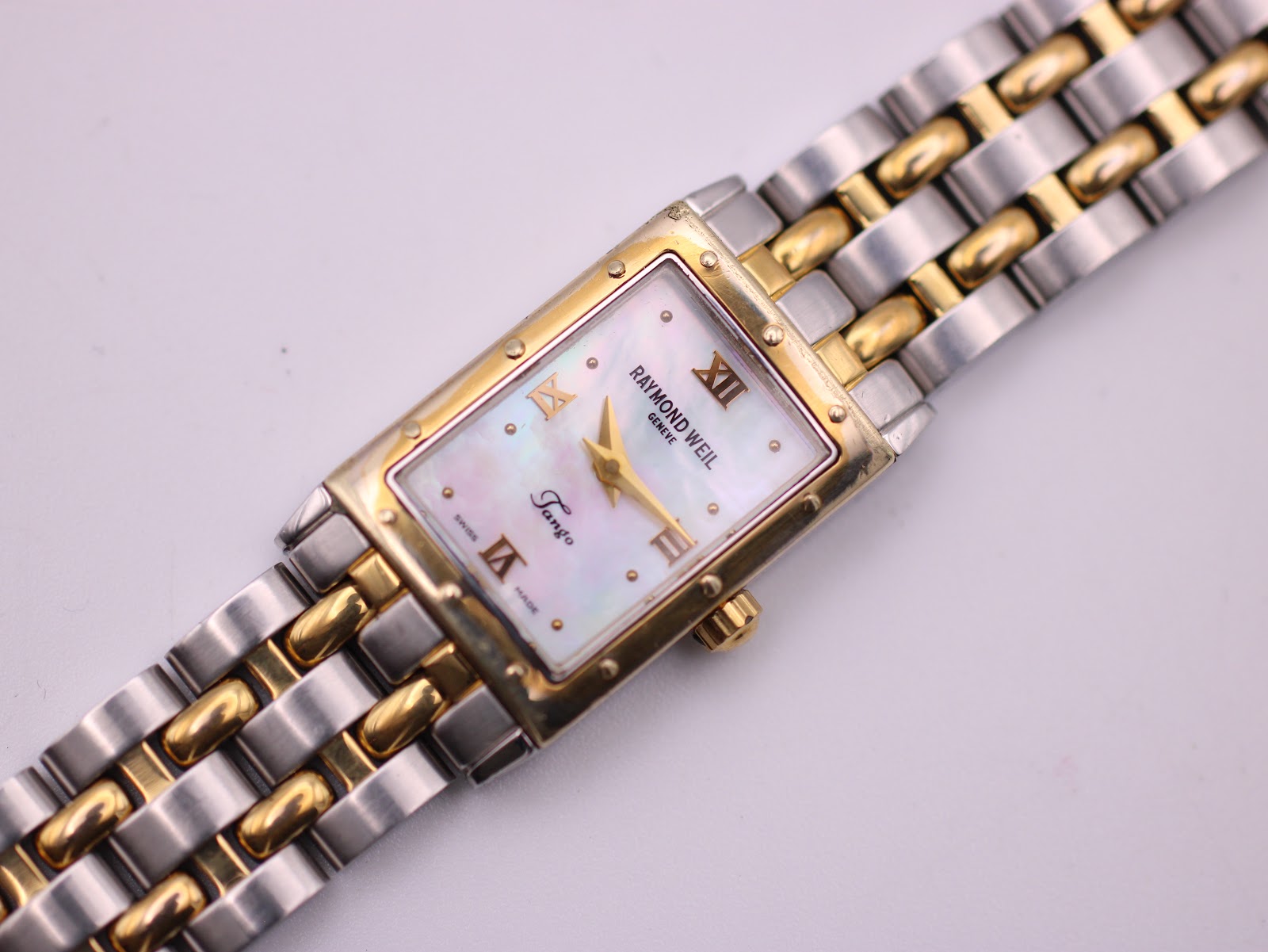 Overhead view of the Raymond Weil Tango watch and its two-tone bracelet laid out on a clean white surface.
