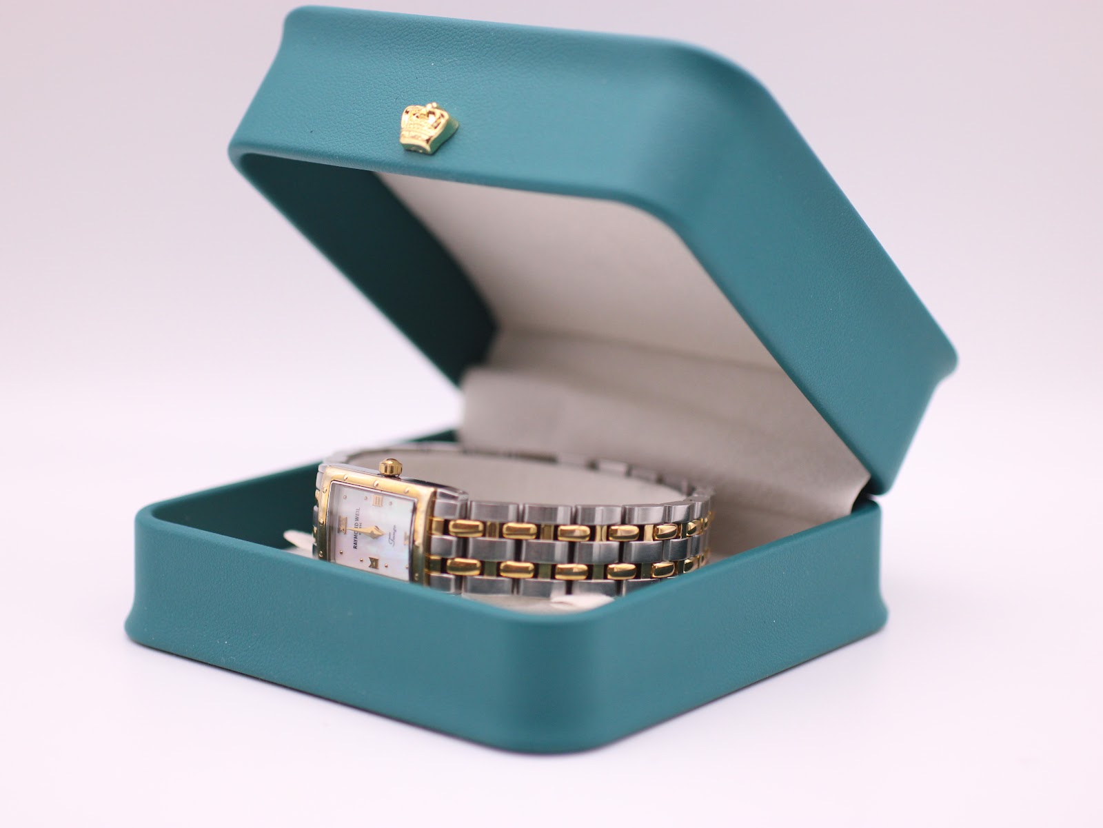The Raymond Weil Tango watch resting inside a green leatherette studio presentation box.