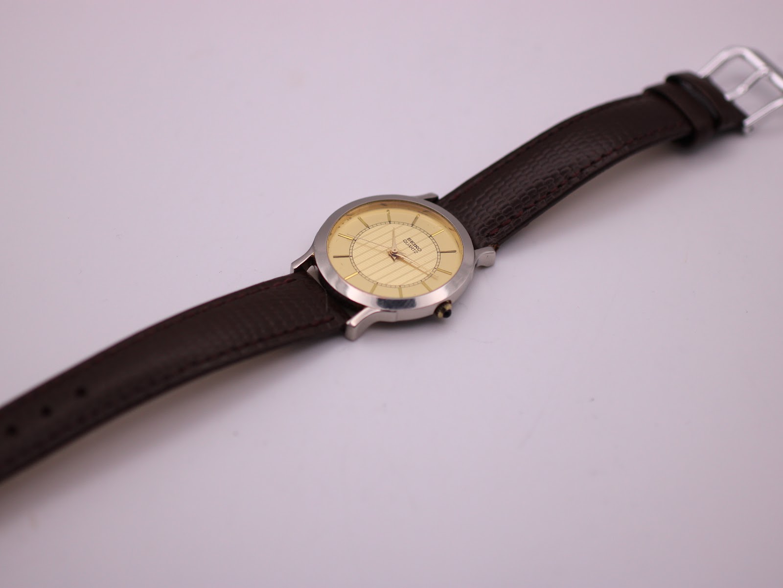 Full length top-down view of the Seiko watch and brown lizard-print leather strap with a silver-tone buckle.