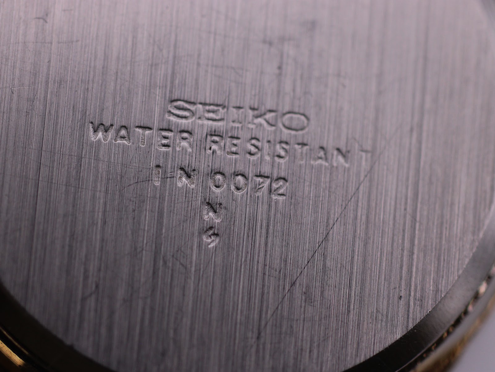 Extreme close-up of the brushed stainless steel case back, showing 'SEIKO WATER RESISTANT' and the serial number '1N0072'.