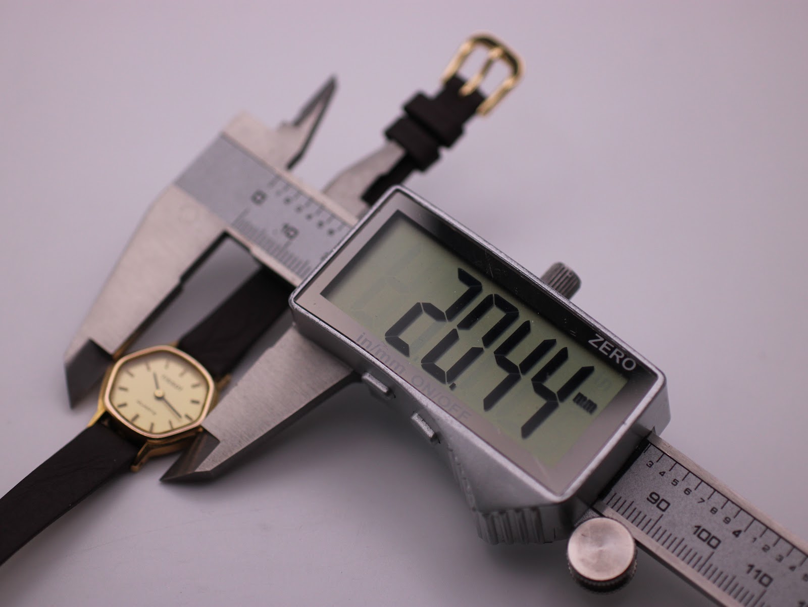 A digital caliper measuring the Tissot watch case, displaying a precise diameter of 20.44mm.