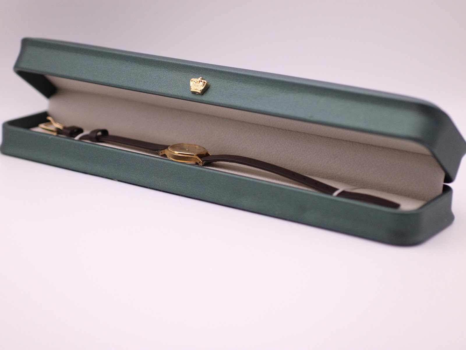 The Tissot watch displayed inside a green leatherette presentation box with a gold crown emblem.