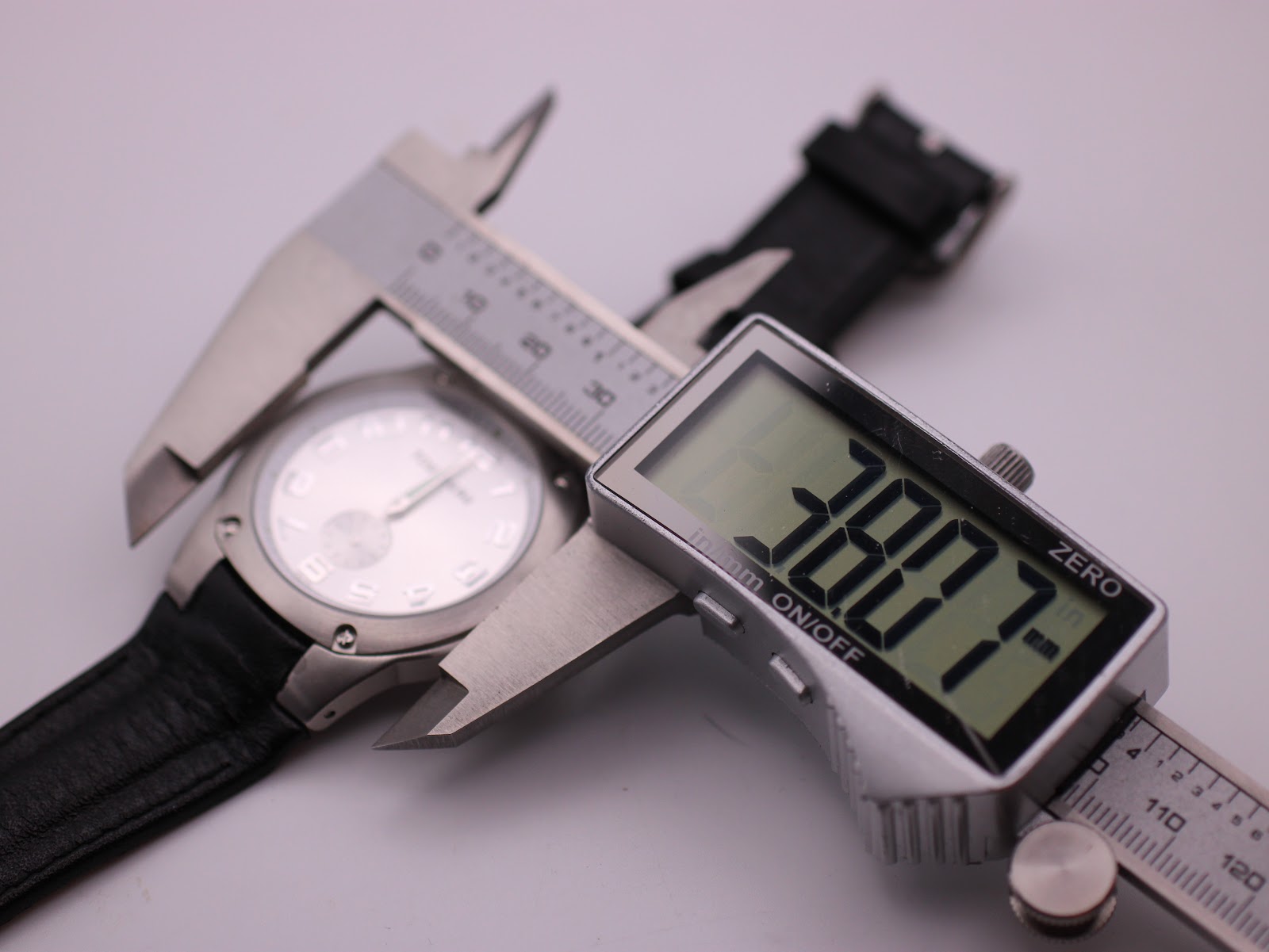 Digital caliper measuring the watch case, displaying a precise diameter of 38.07mm.