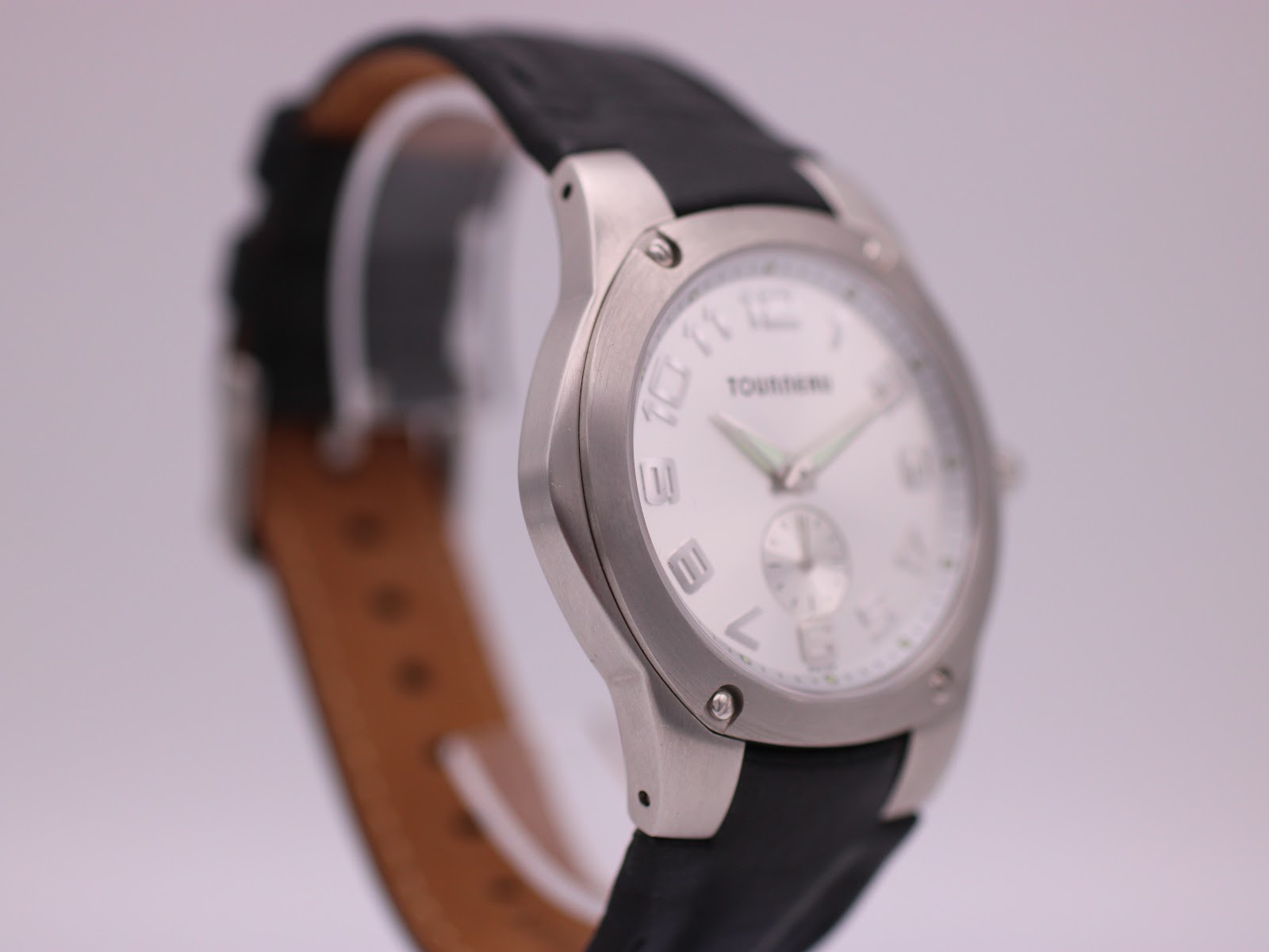 Oblique side view of the watch on a stand, showing the case profile and strap.