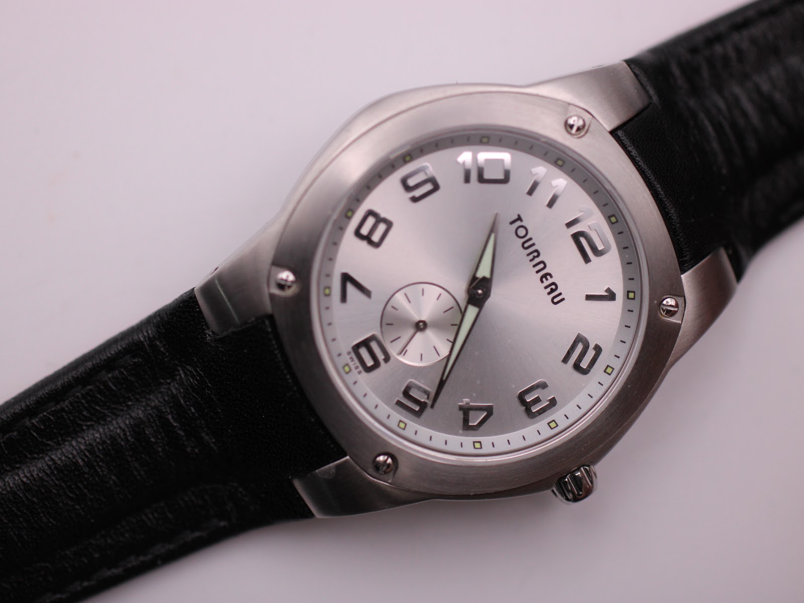 Close-up top-down view of the watch dial, strap, and case, focusing on the details of the silver face and black strap texture.