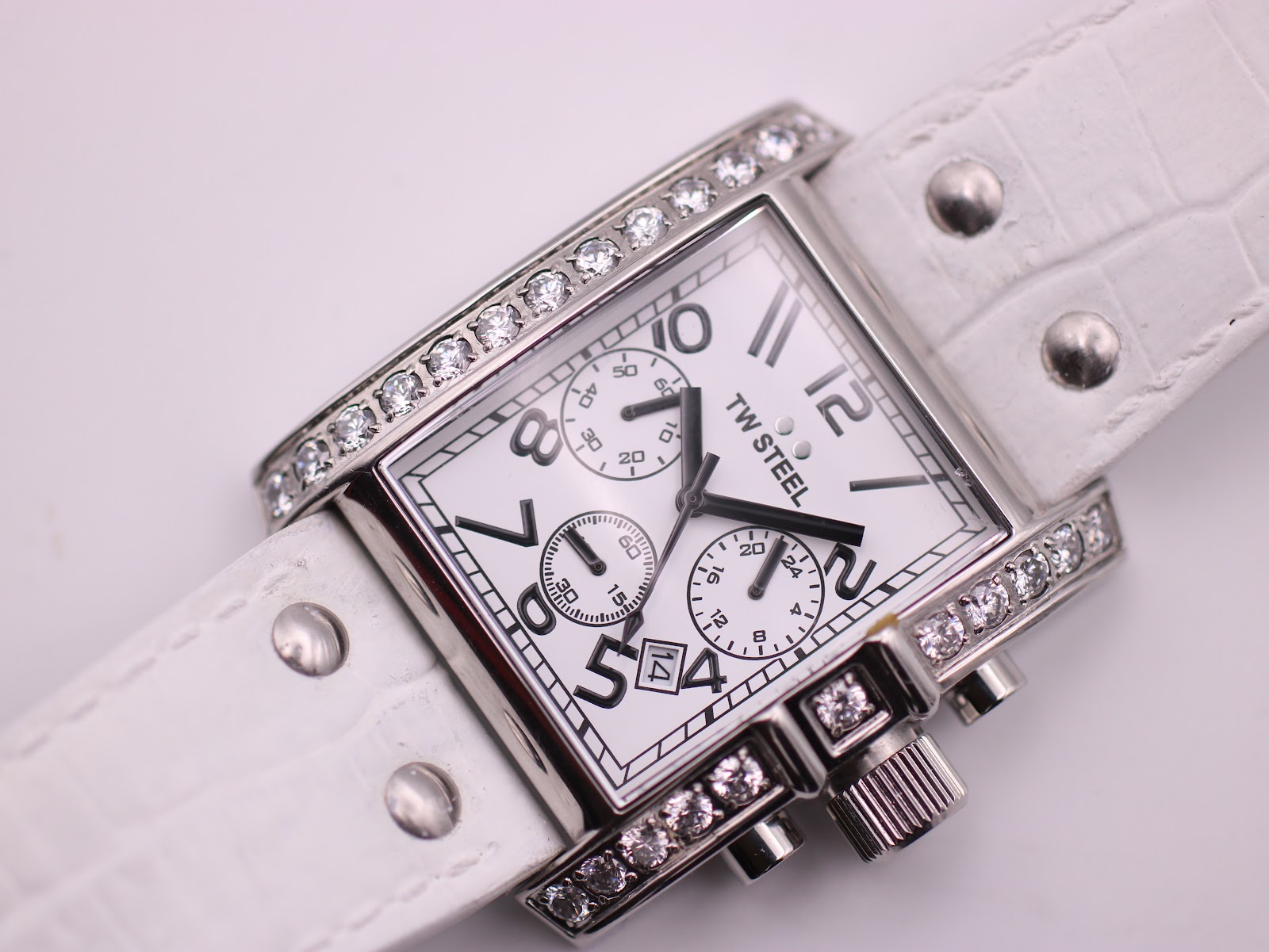 Overhead close-up of the dial, white alligator-pattern leather strap, and case details.