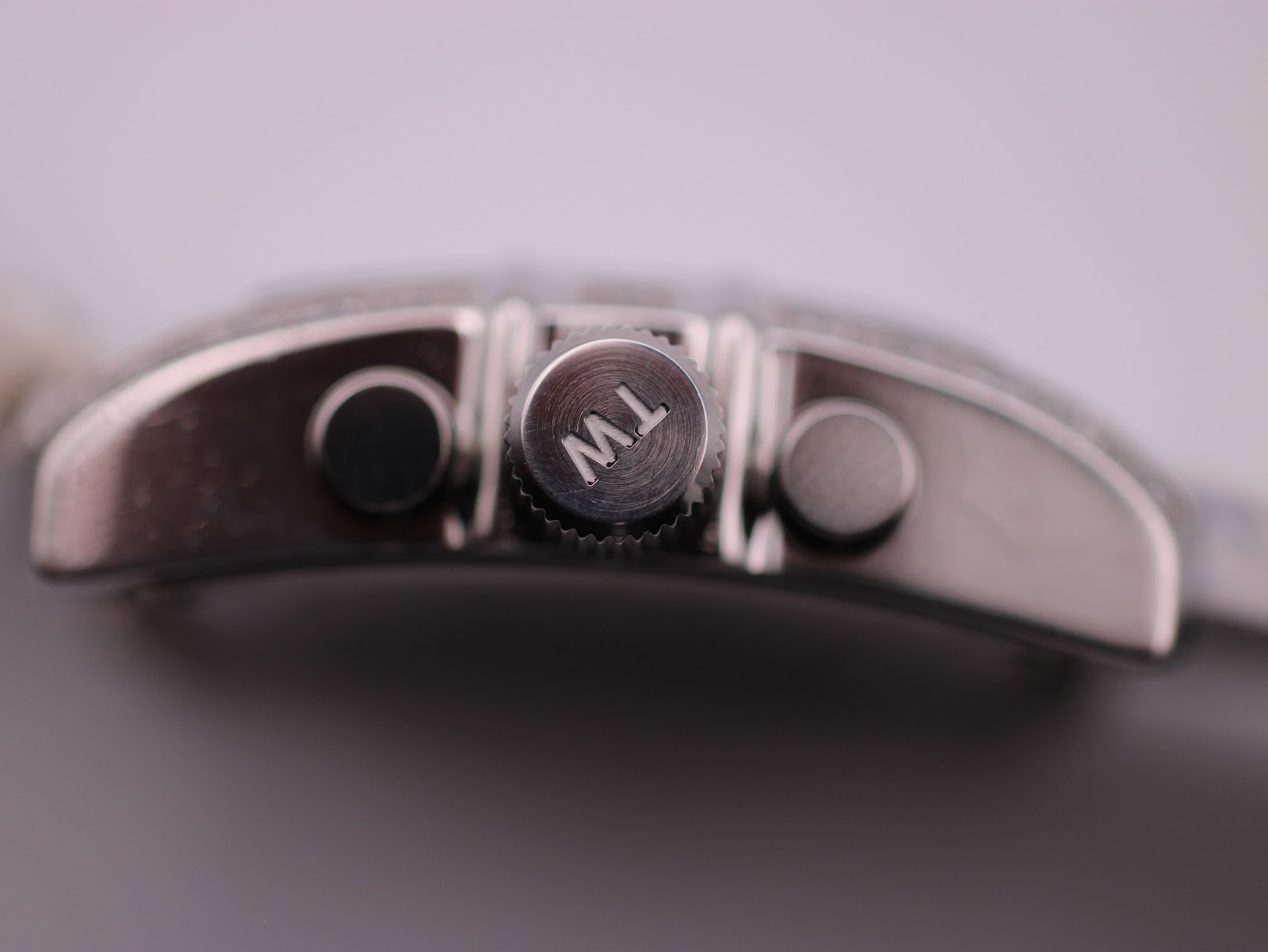 Close-up of the polished crown with engraved 'TW' logo and chronograph pushers.