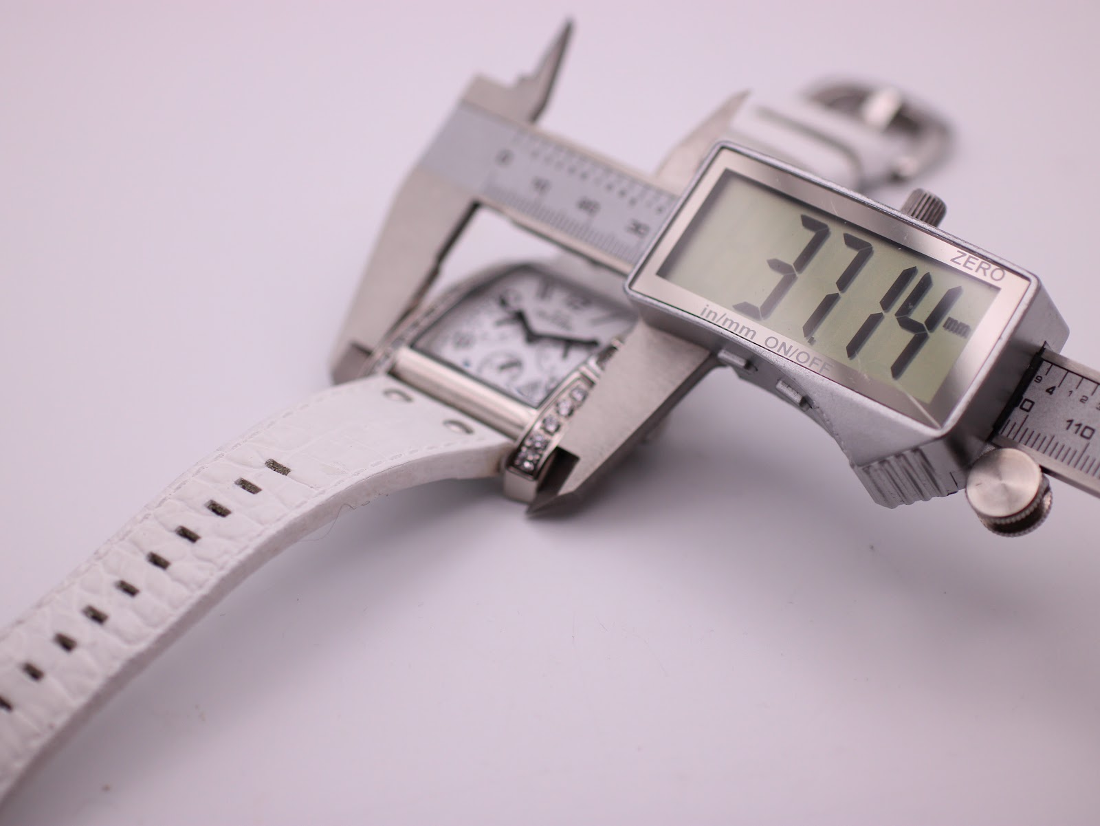 Digital caliper measuring the case diameter of the rectangular watch as 37.14mm.