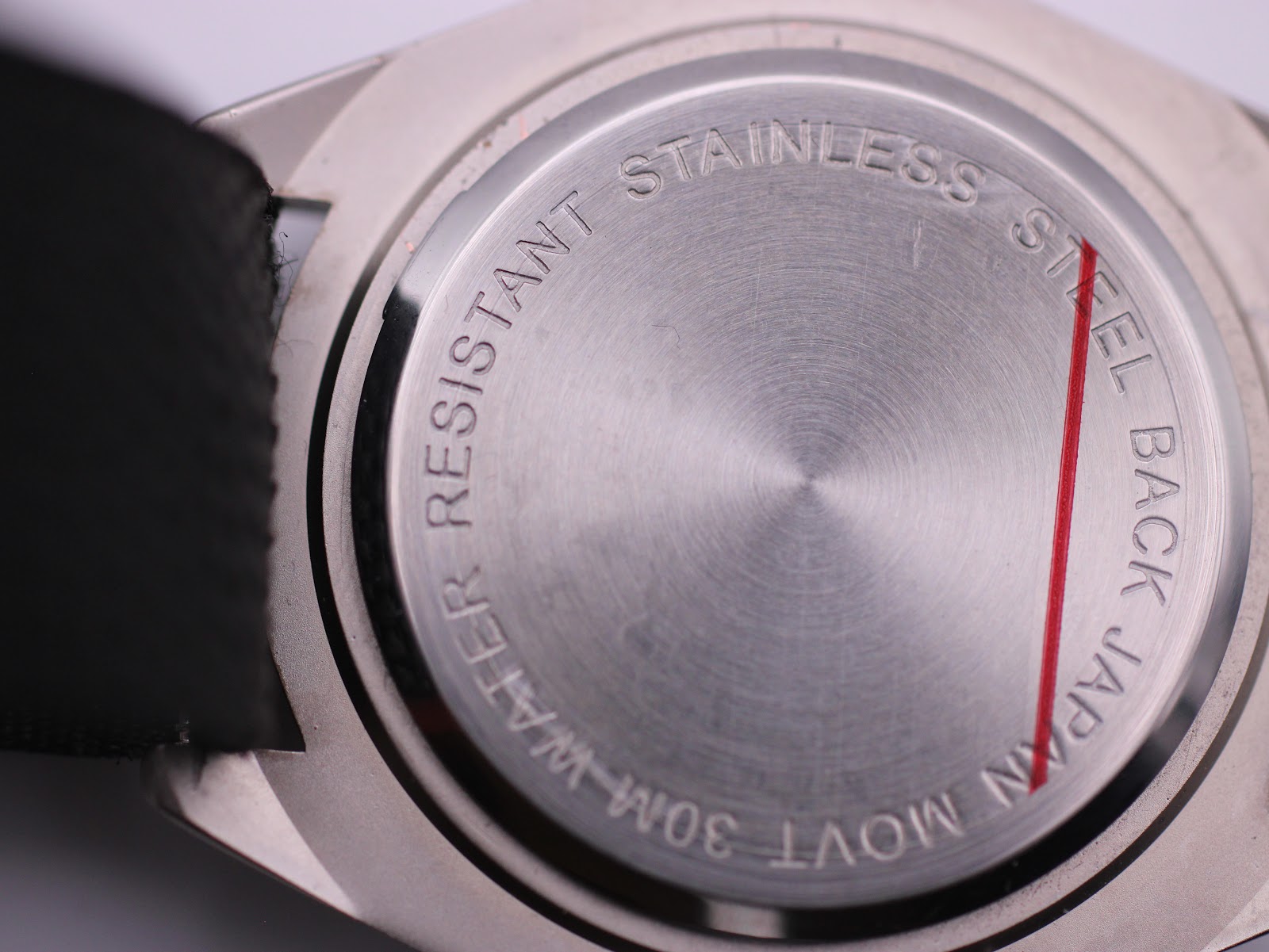 Detailed close-up of the polished stainless steel case back, with engravings 'WATER RESISTANT 30M JAPAN MOVT STAINLESS STEEL BACK'.