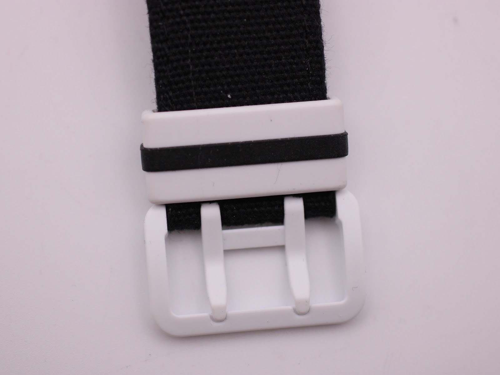 Close-up of the white resin buckle and keepers on the black NATO strap.