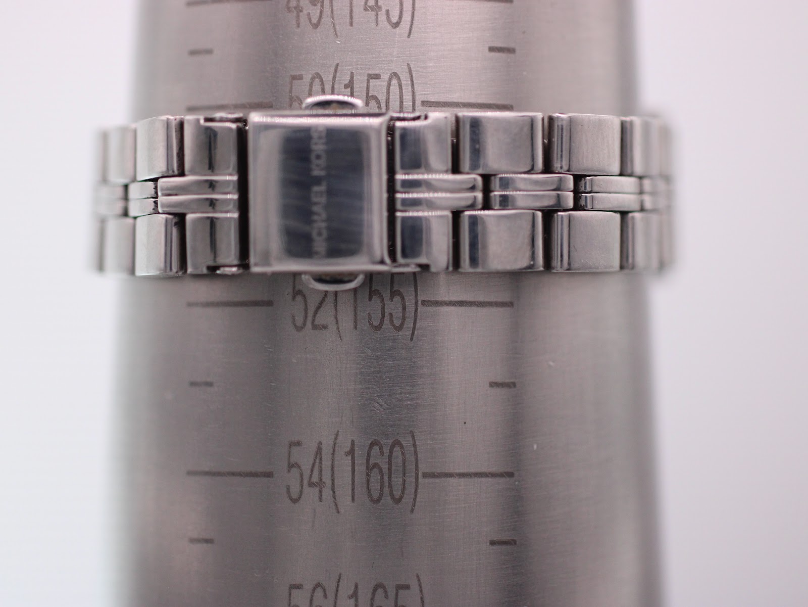 Michael Kors watch bracelet wrapped around a wrist sizing gauge, showing a measurement of 150mm or 15cm.