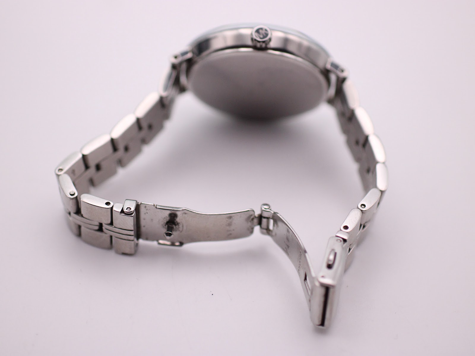 Underneath view of the Michael Kors watch bracelet with the fold-over clasp open.