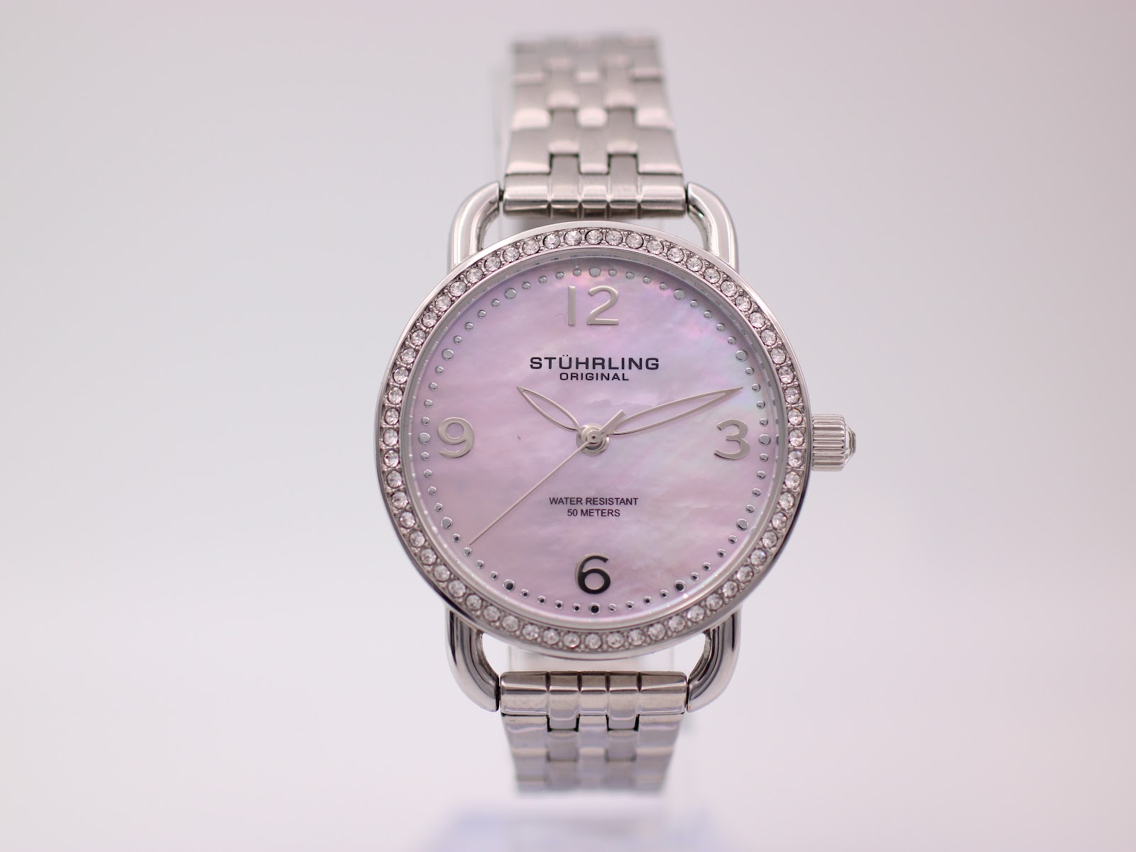 Front view of Stührling Original watch with pink mother-of-pearl dial, crystal-set bezel, and stainless steel bracelet.