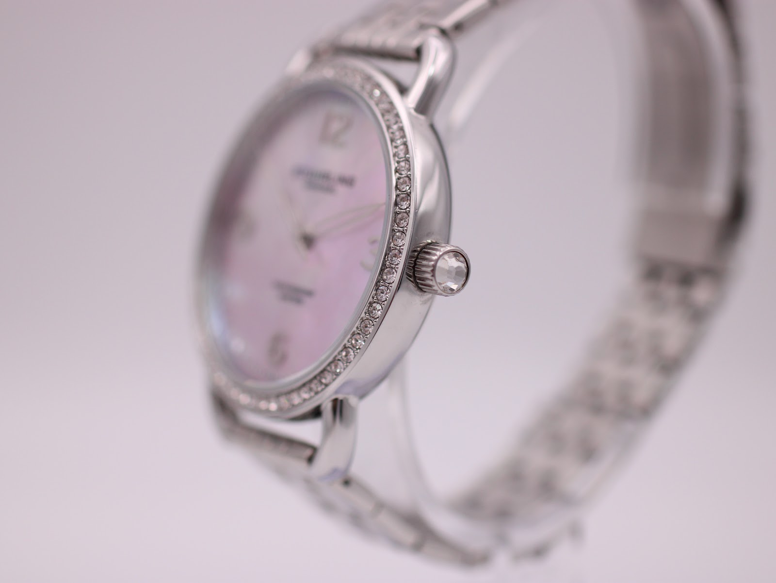 Angled close-up of the Stührling Original watch showing the crystal-set bezel, textured crown, and side of the polished case.