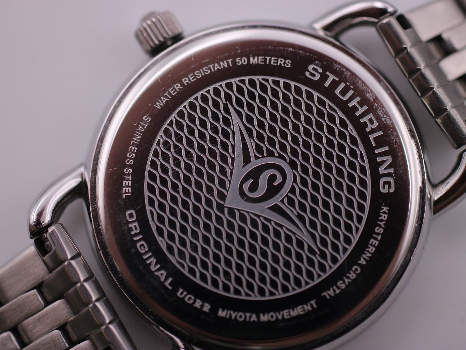Close-up of the polished stainless steel case back with "STÜHRLING ORIGINAL", "WATER RESISTANT 50 METERS", "KRYSTERNA CRYSTAL", "MIYOTA MOVEMENT", and logo engraving.