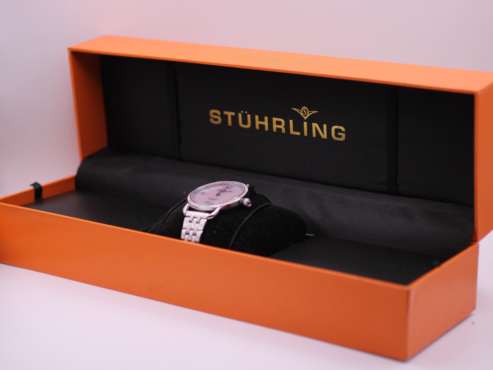 Stührling Original watch nestled on a cushion inside its orange original presentation box with gold branding.