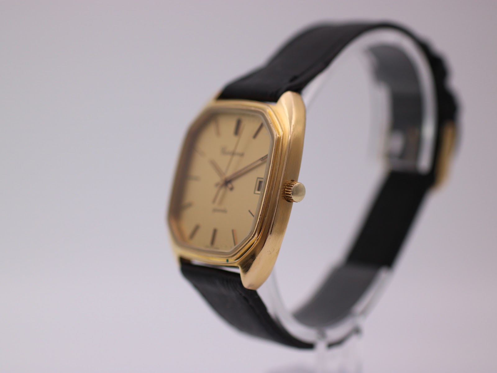 Side angled view of the Certina Newport watch, showing the gold case and crown, on a display stand.