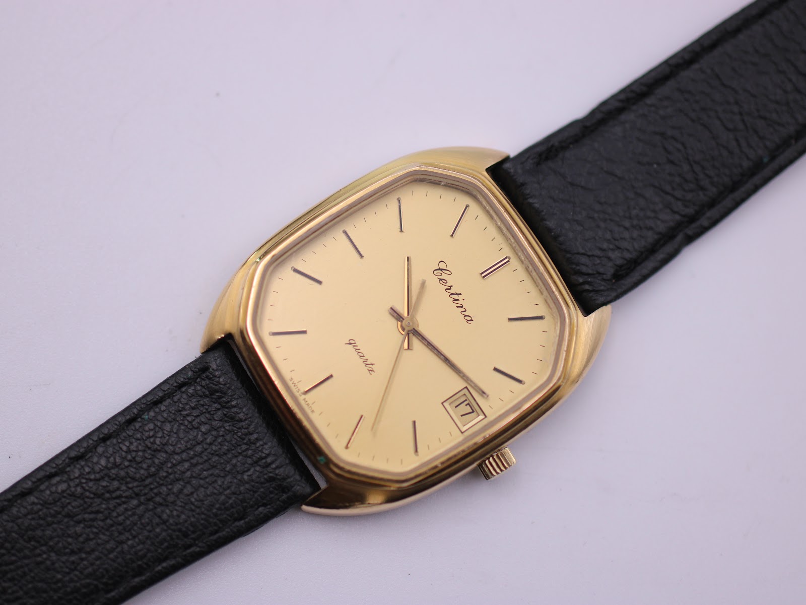 Close-up angled view of the Certina Newport watch dial and black leather strap on a white background.