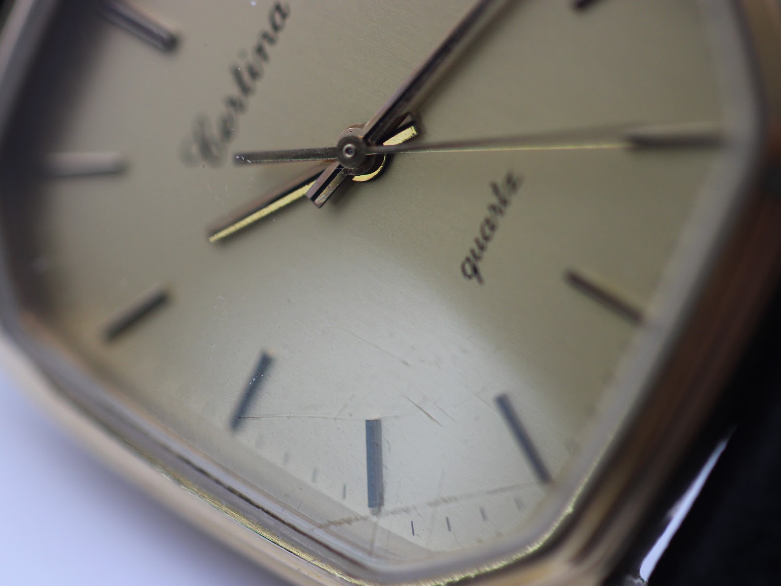 Extreme close-up of the Certina Newport champagne dial and crystal, showing light surface scratches on the crystal.