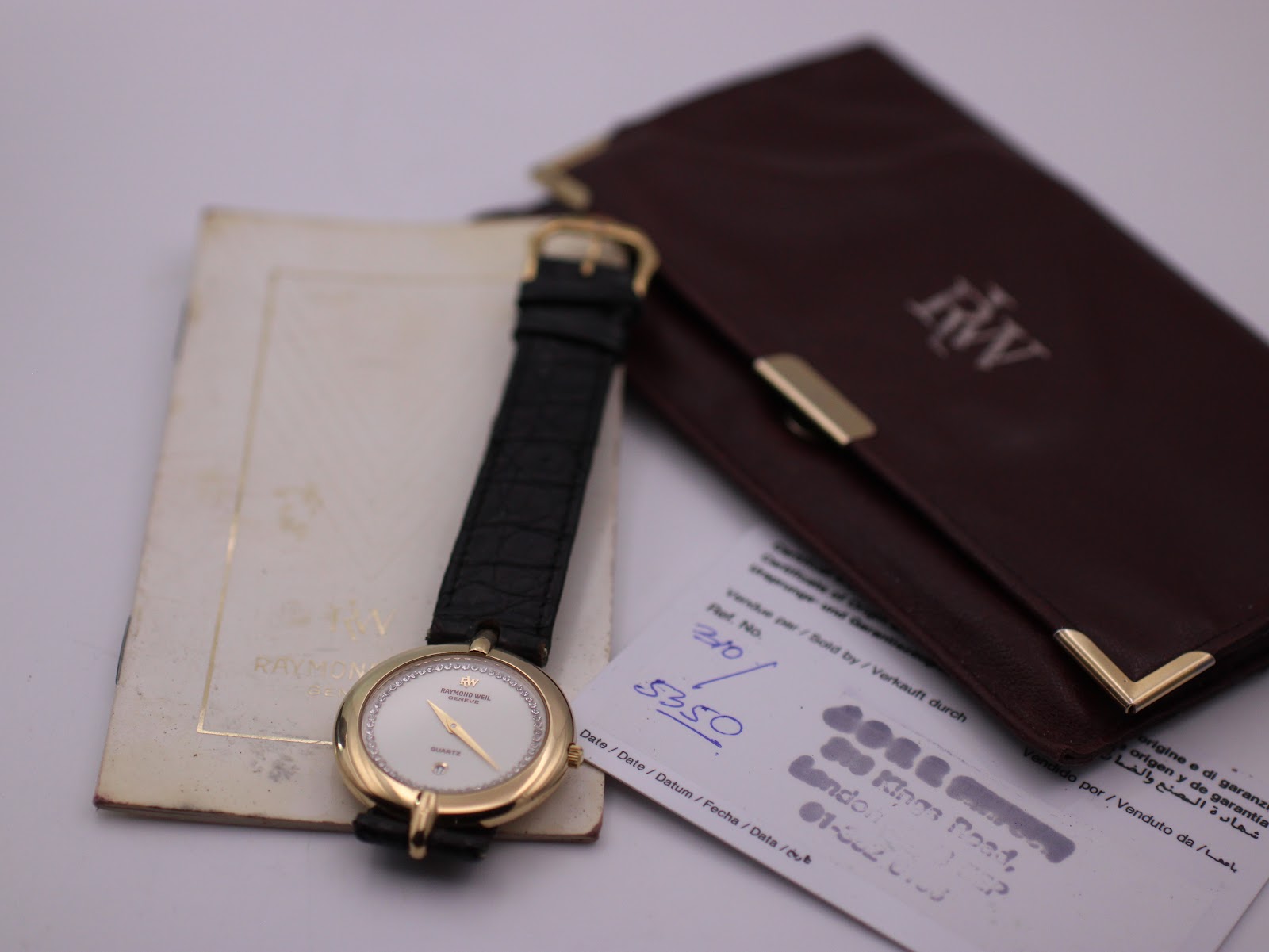 Raymond Weil 5350 watch displayed alongside its original brown document holder and papers.