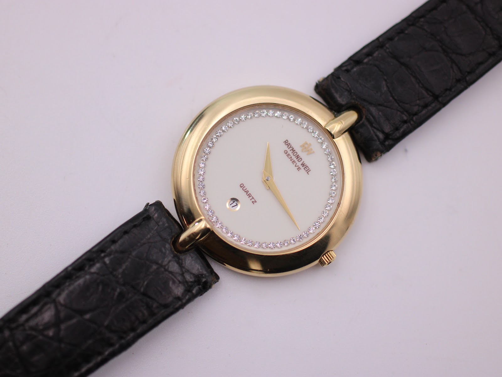 Close-up front view of the Raymond Weil 5350 white dial with gold hands, date window, and diamond-set inner bezel.