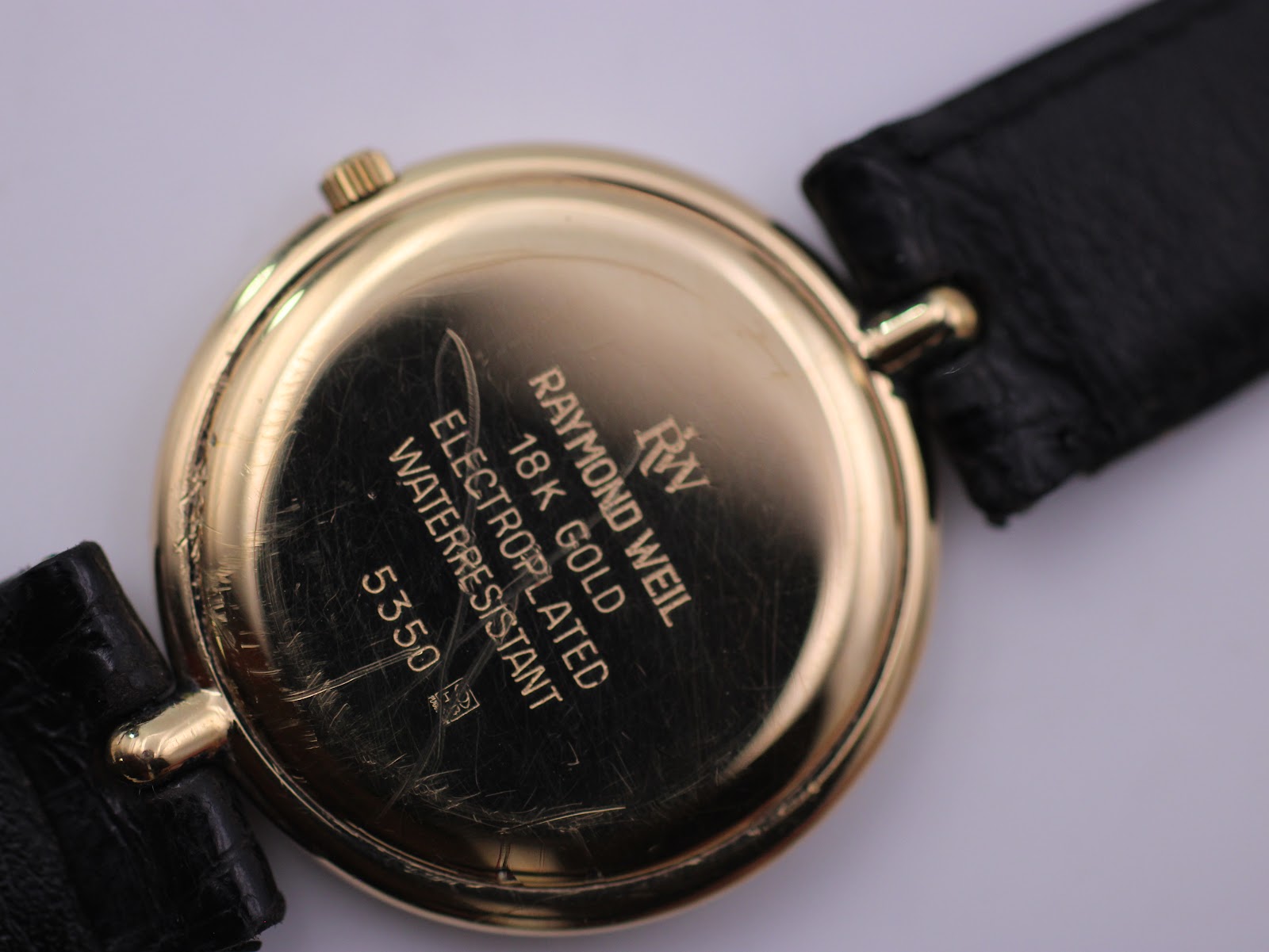 Close-up of the gold-tone case back showing 'Raymond Weil', '18K Gold Electroplated', 'Waterresistant', and model '5350' engravings.