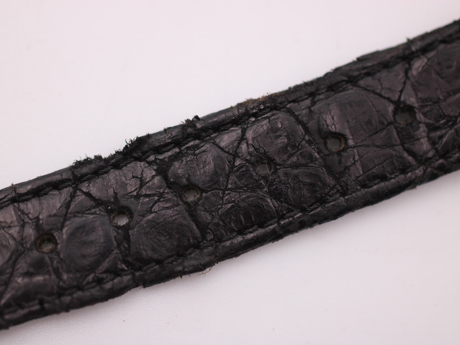 Close-up of the black leather strap's crocodile-effect texture and signs of wear.