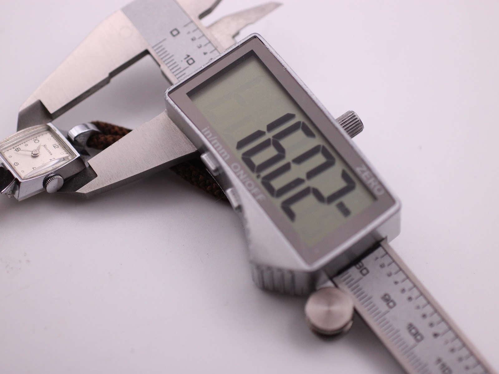 Digital caliper measuring the width of the Helvetia watch case, with the display showing an exact measurement of 16.22mm.