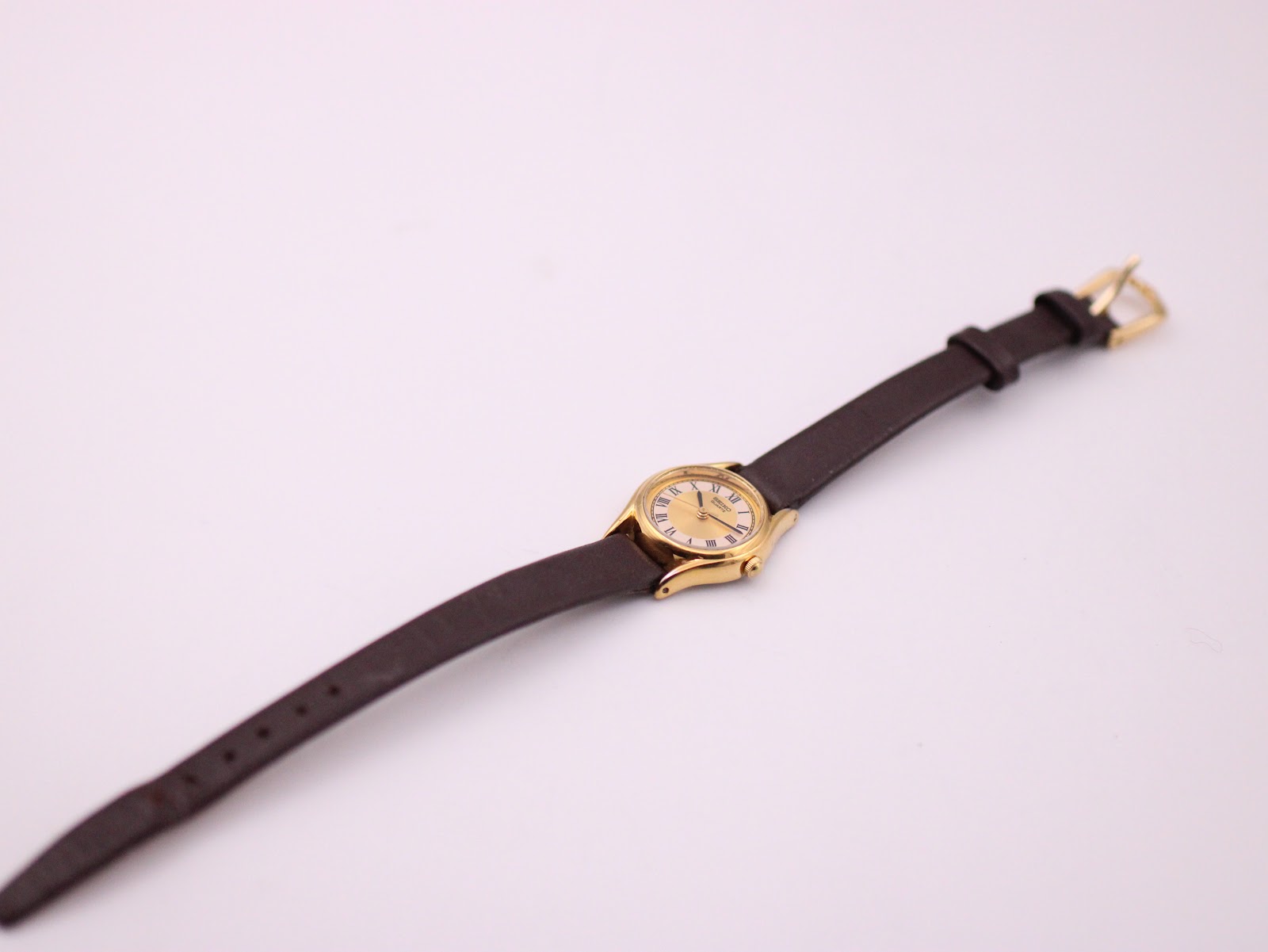 Top-down view of the Seiko watch laid flat, displaying the full brown leather strap and gold-tone buckle.