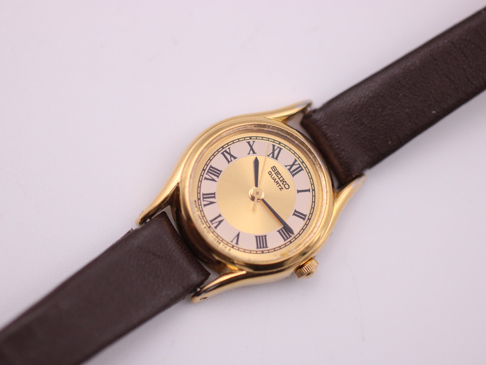 Close-up of the Seiko gold-tone dial with cream outer track and black Roman numerals.