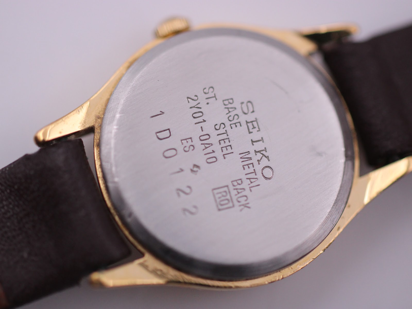 Detailed close-up of the stainless steel case back with Seiko engravings: 'BASE METAL', 'ST. STEEL BACK', '2Y01-0A10', and serial '1D0122'.