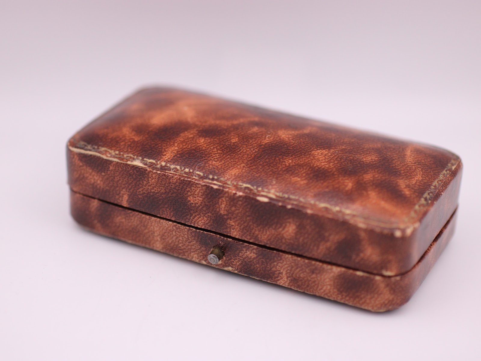 Closed view of the vintage brown presentation box with a textured faux leather finish.