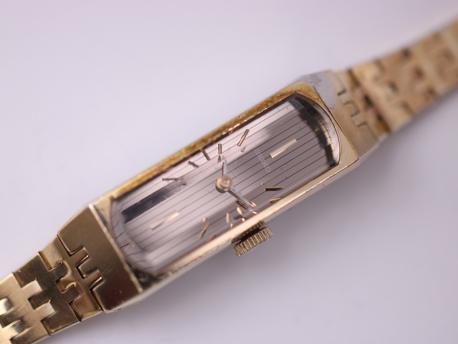 Close-up top-down view of the Seiko watch dial and fluted crown, emphasising the vertical brushed texture.