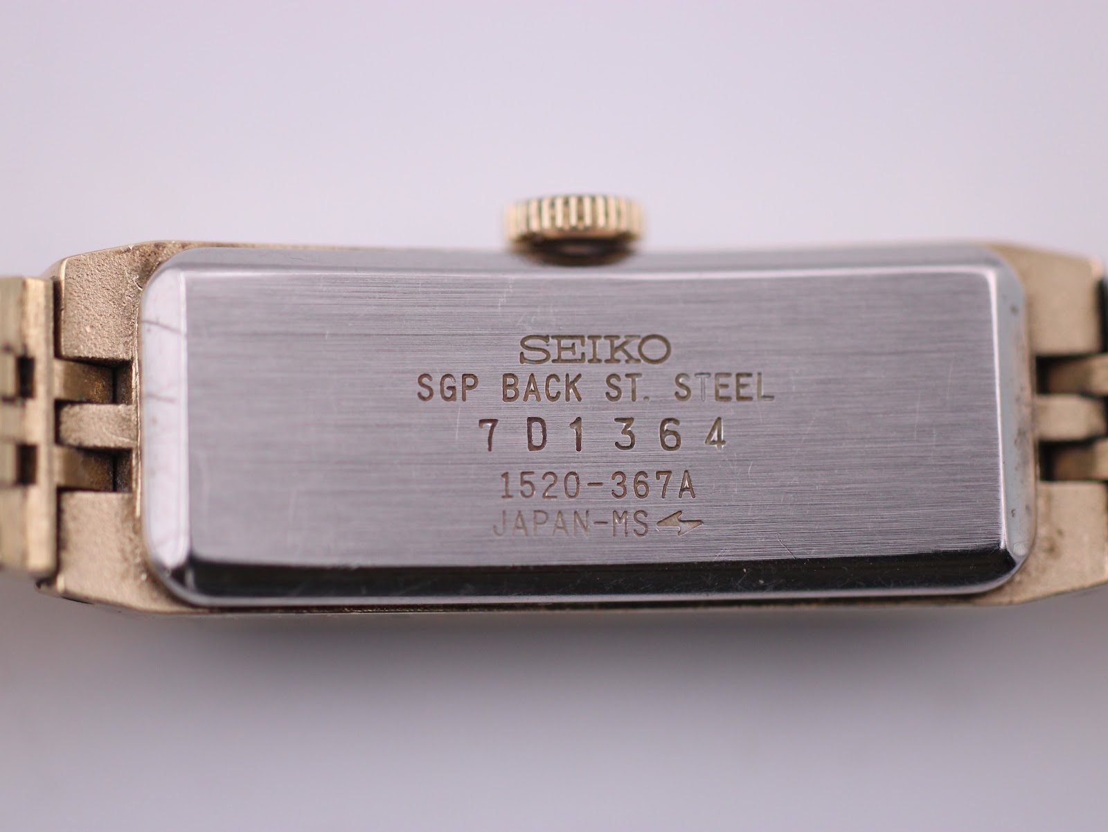 Clear close-up of the watch case back, showing 'SEIKO SGP BACK ST. STEEL' engraving and model/serial numbers.