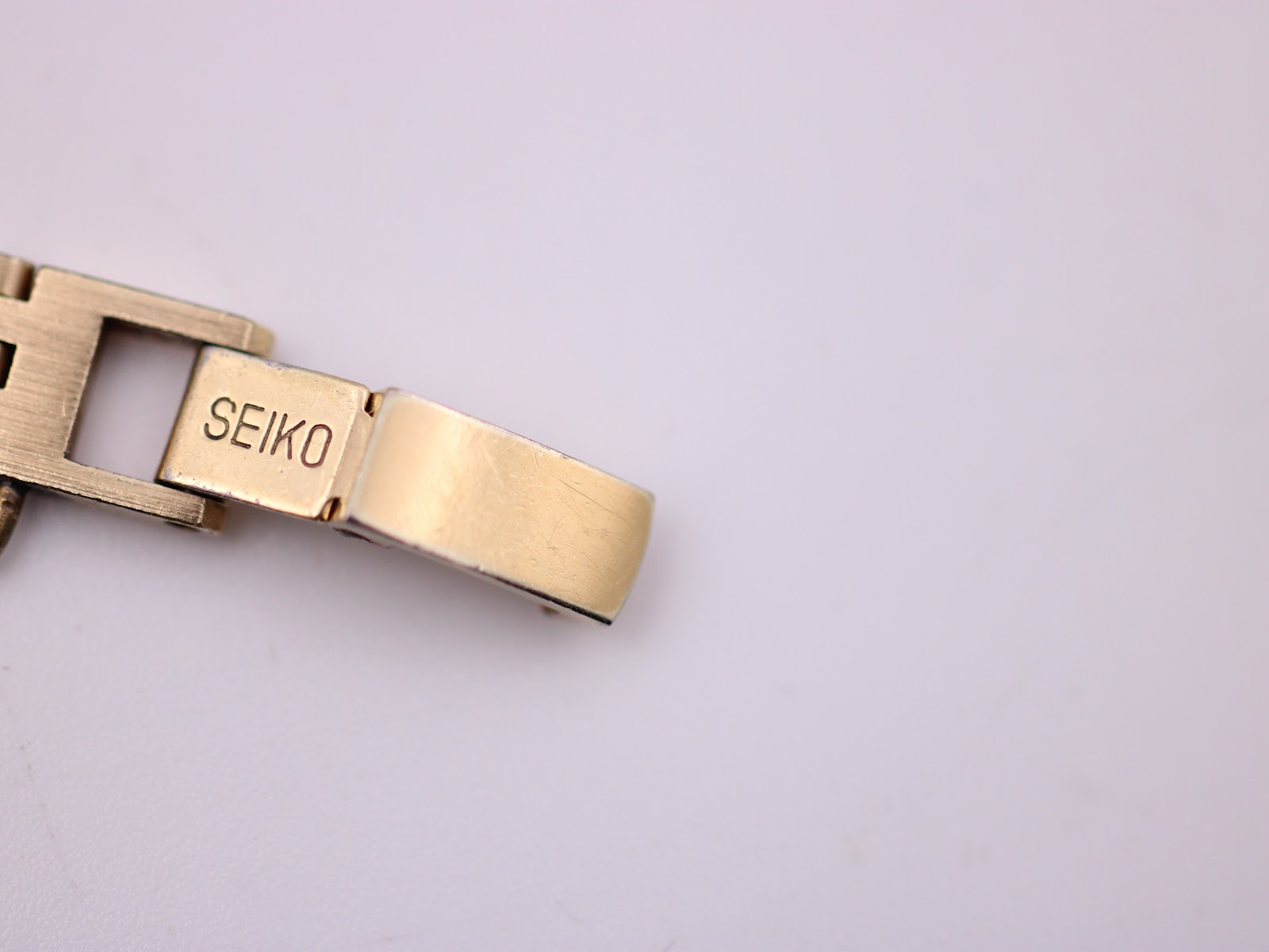 Close-up of the gold tone steel bracelet clasp, clearly showing the 'SEIKO' signed engraving.