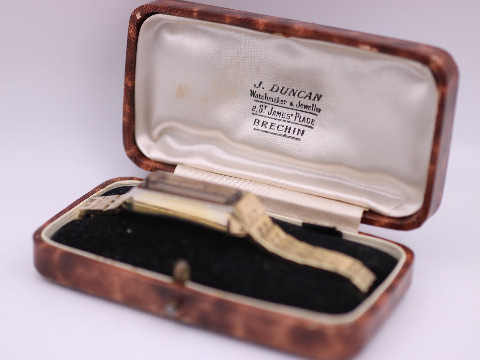 The Seiko watch resting inside an open vintage brown presentation box with 'J. Duncan Watchmaker & Jeweller' printed on the lid's satin lining.