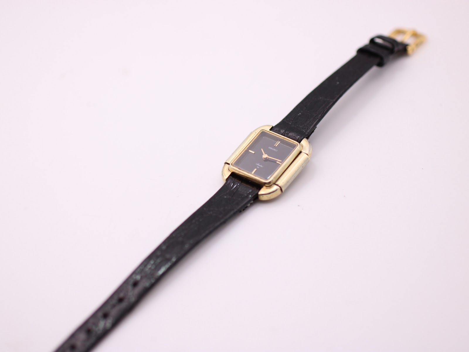 Full length view of the Seiko Socie watch with its black leather strap, laid flat against a white background.