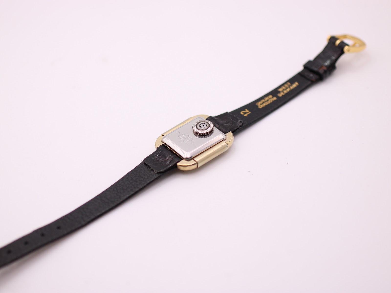 Rear view of the Seiko Socie watch on a stand, showing the stainless steel case back and the interior of the black leather strap.