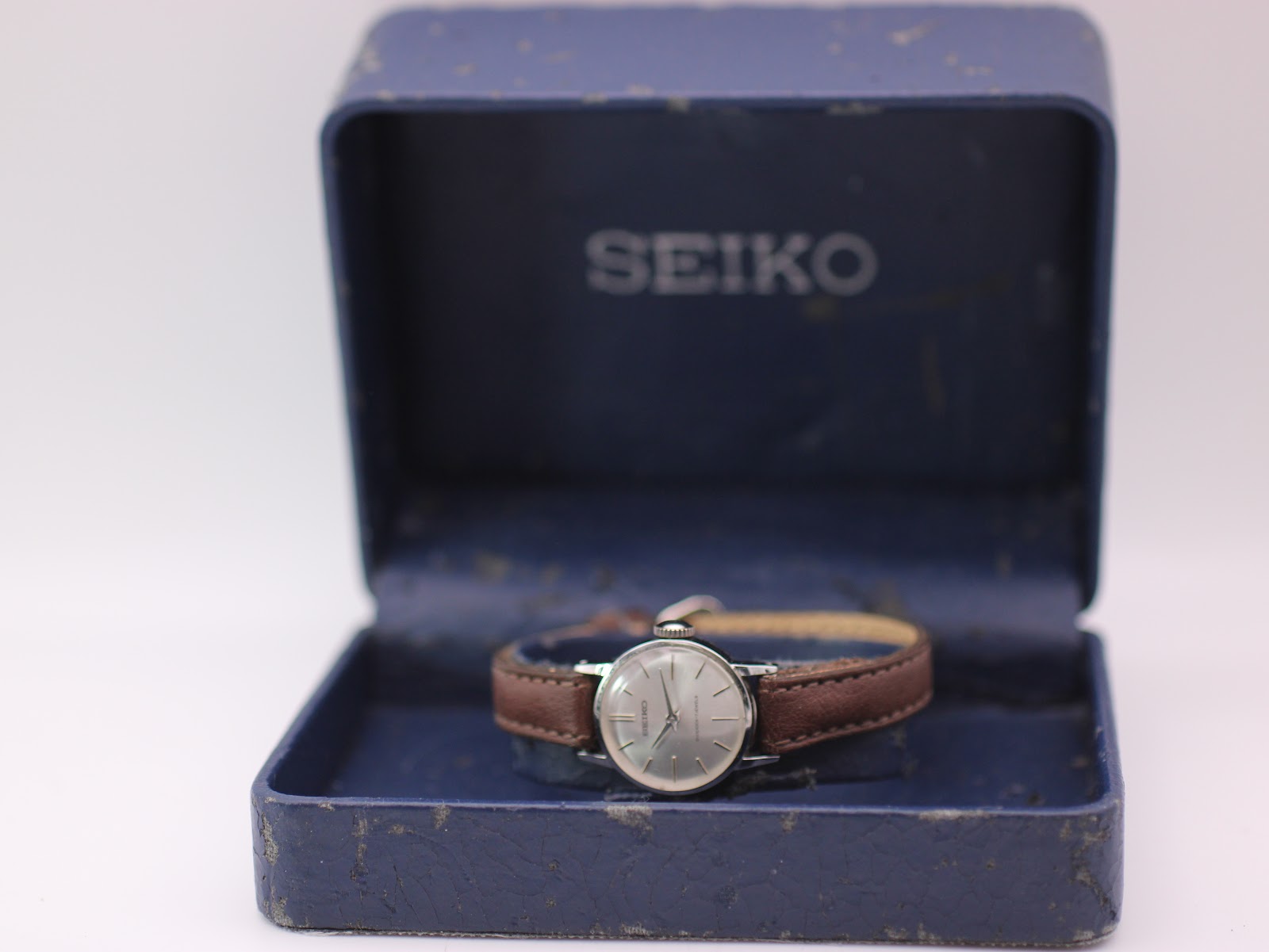 The vintage Seiko watch sitting inside its original, worn blue Seiko presentation box.