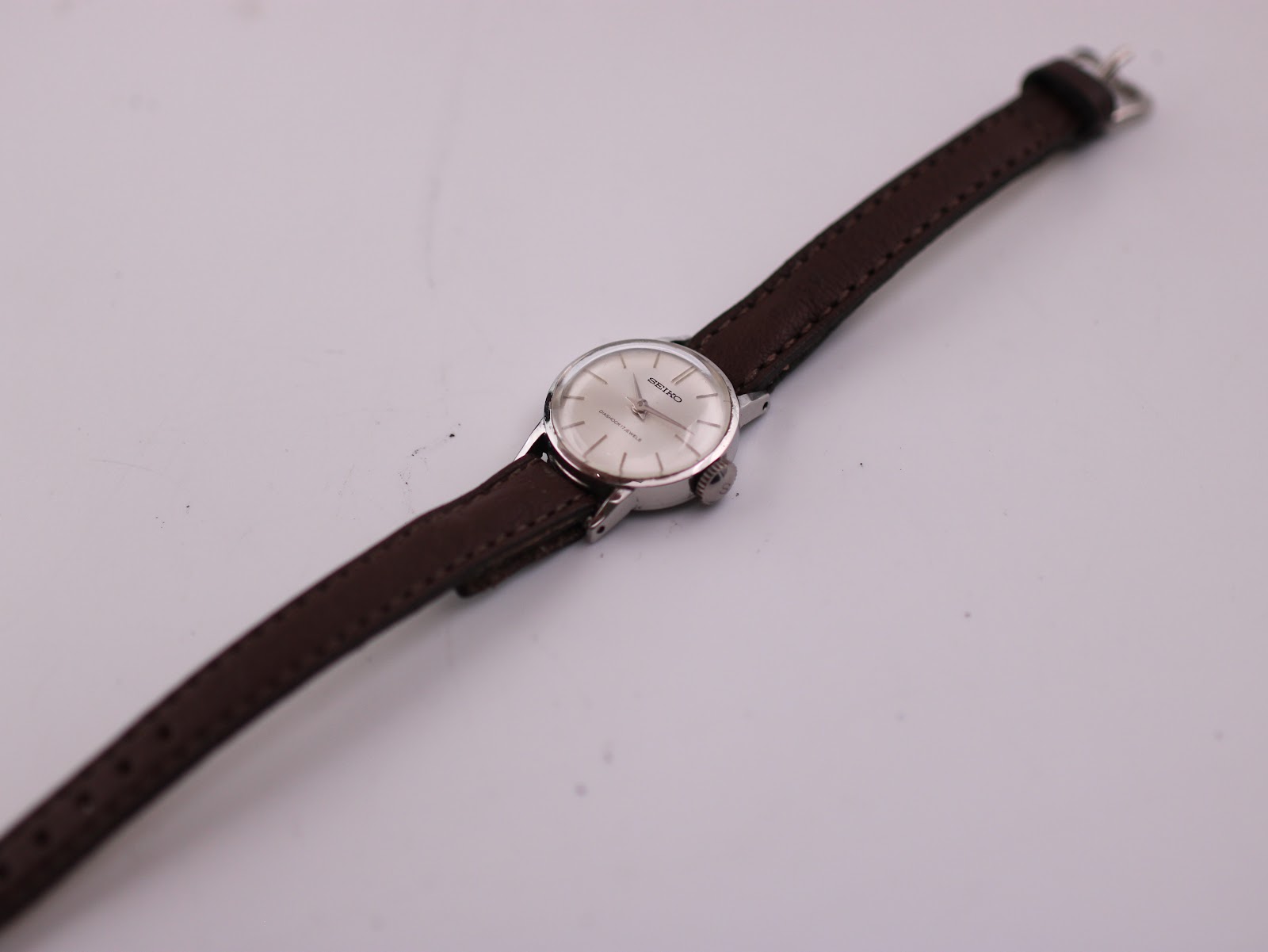 Overhead view of the Seiko watch and brown leather strap extended on a white surface.