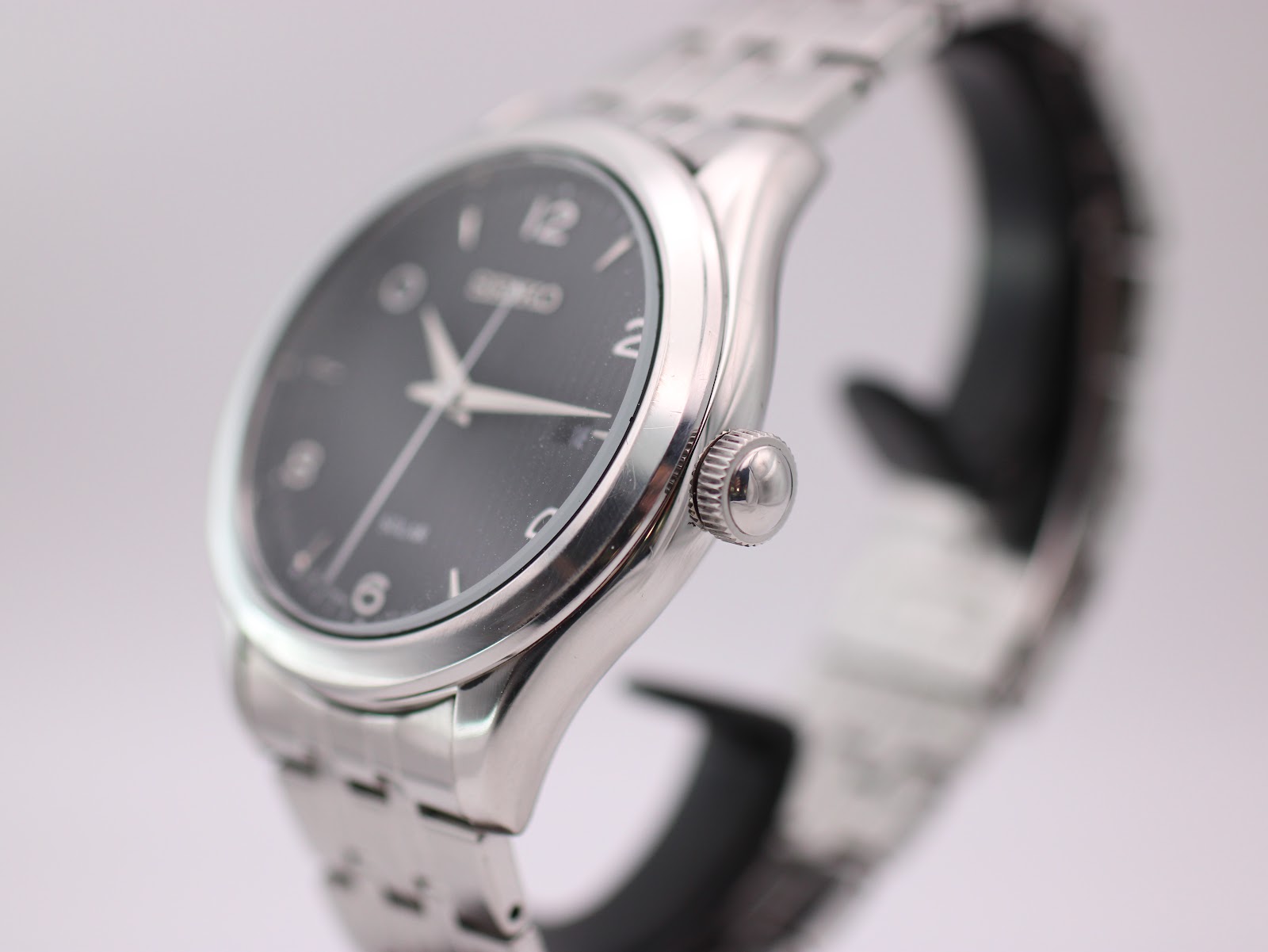 Angled side view showing the polished stainless steel case and crown of the Seiko V157-0CNO.