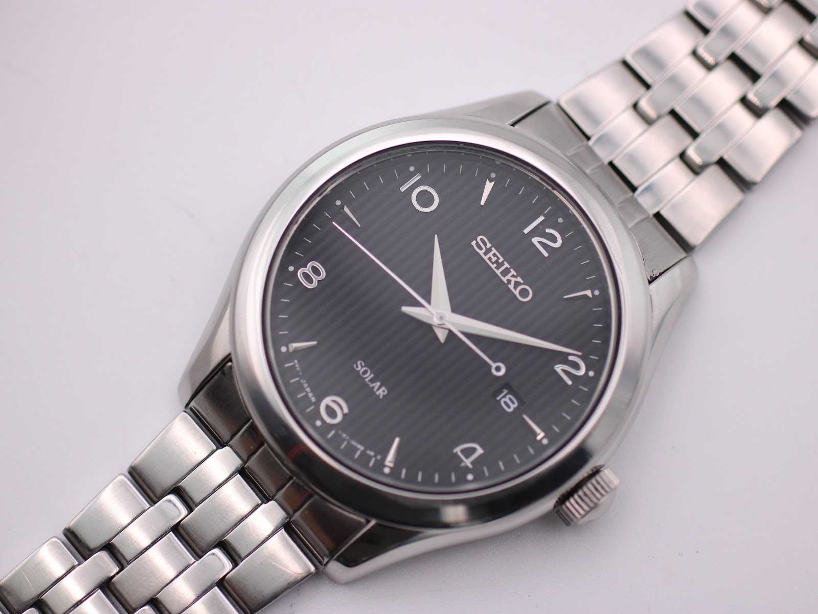 Overhead angled view of the Seiko solar watch, showing the dial and bracelet links.