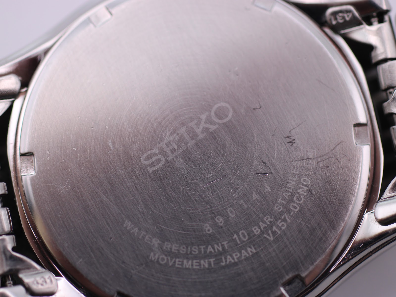 Close-up of the brushed stainless steel case back with Seiko logo, serial number 890144, water resistance, and movement details.