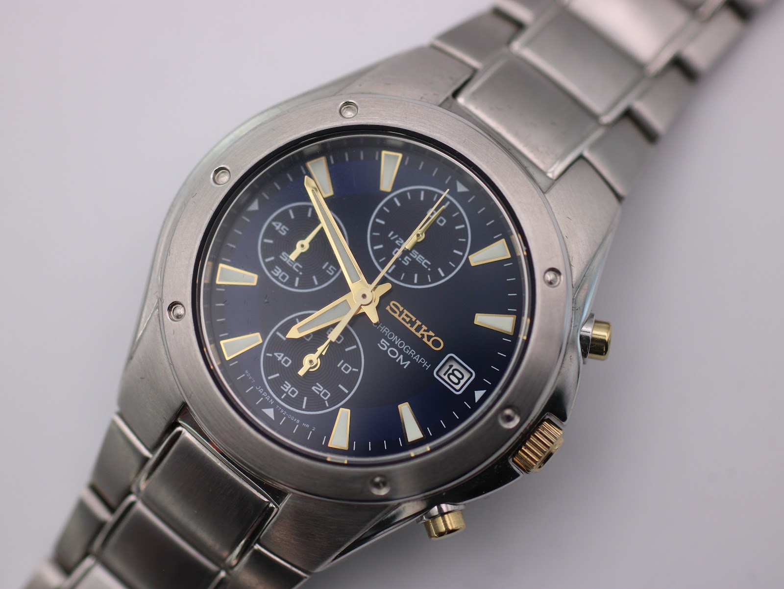 Close-up of the Seiko blue chronograph dial, detailing the sub-dials, gold baton indices, and hands.
