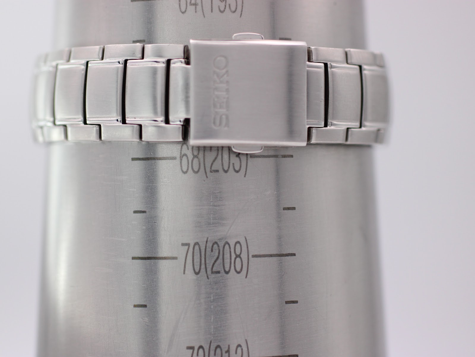 The stainless steel bracelet of the Seiko watch on a wrist sizing gauge, indicating a wrist circumference of approximately 20.3cm.