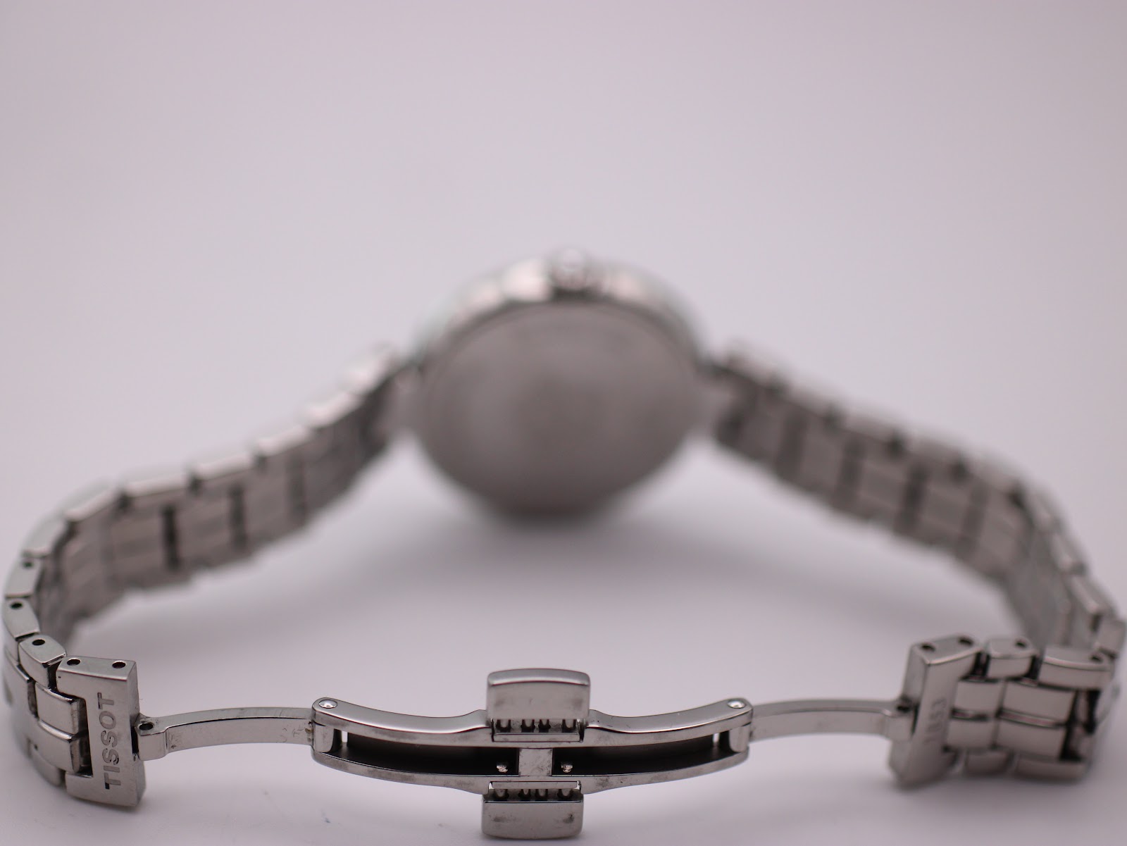 Rear view of the opened stainless steel butterfly deployant clasp with "TISSOT" engraved, and bracelet links.