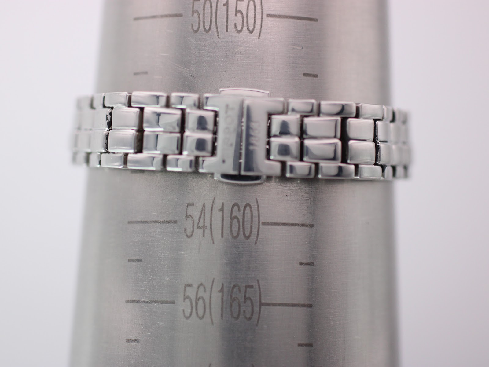 Close-up of the Tissot stainless steel bracelet and clasp on a wrist sizing gauge, indicating a wrist circumference of 160mm (16cm).