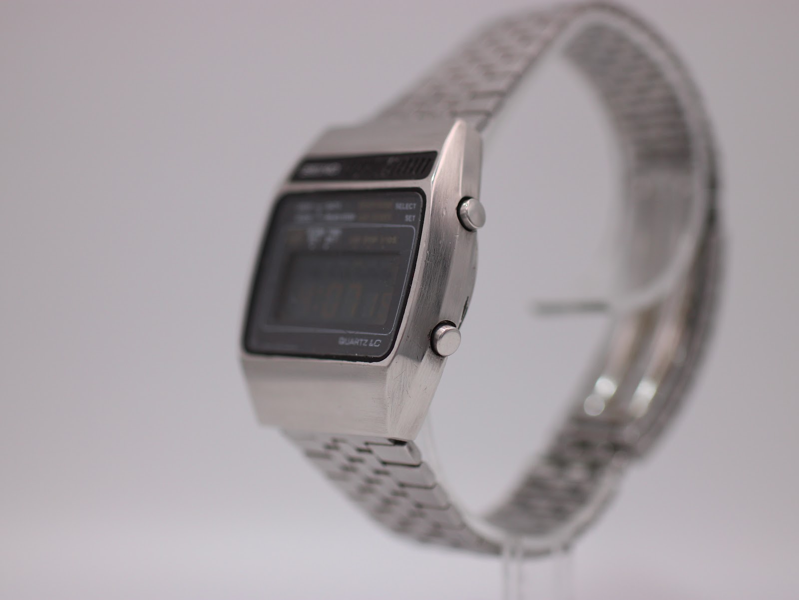 Angled side view of the Seiko A159-5009-G watch, highlighting the brushed stainless steel case and pushers on the right side.