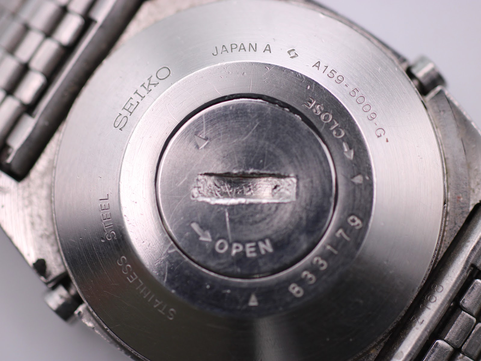 Detailed close-up of the Seiko A159-5009-G stainless steel case back, showing model A159-5009-G, serial 833179, 'JAPAN A', and 'STAINLESS STEEL' engravings.