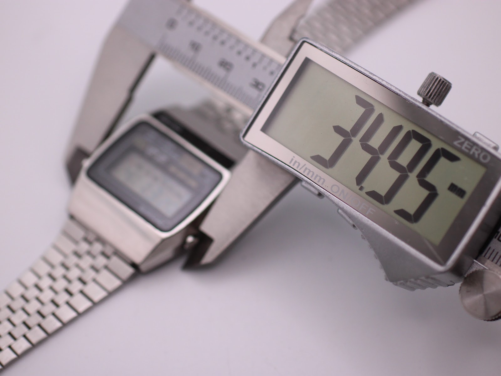 Digital caliper measuring the case width of the Seiko A159-5009-G watch, showing an exact measurement of 34.95mm on the display.